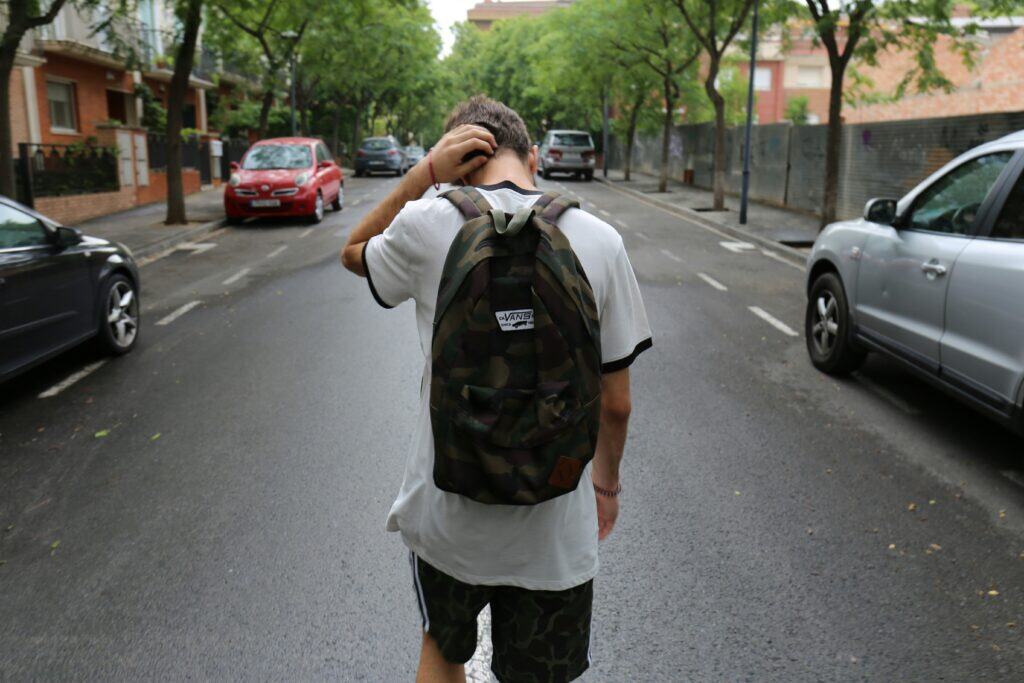 Signs of child abuse may include withdrawing from friends or sudden changes in school performance, like this teen who walks the street alone with his backpack.