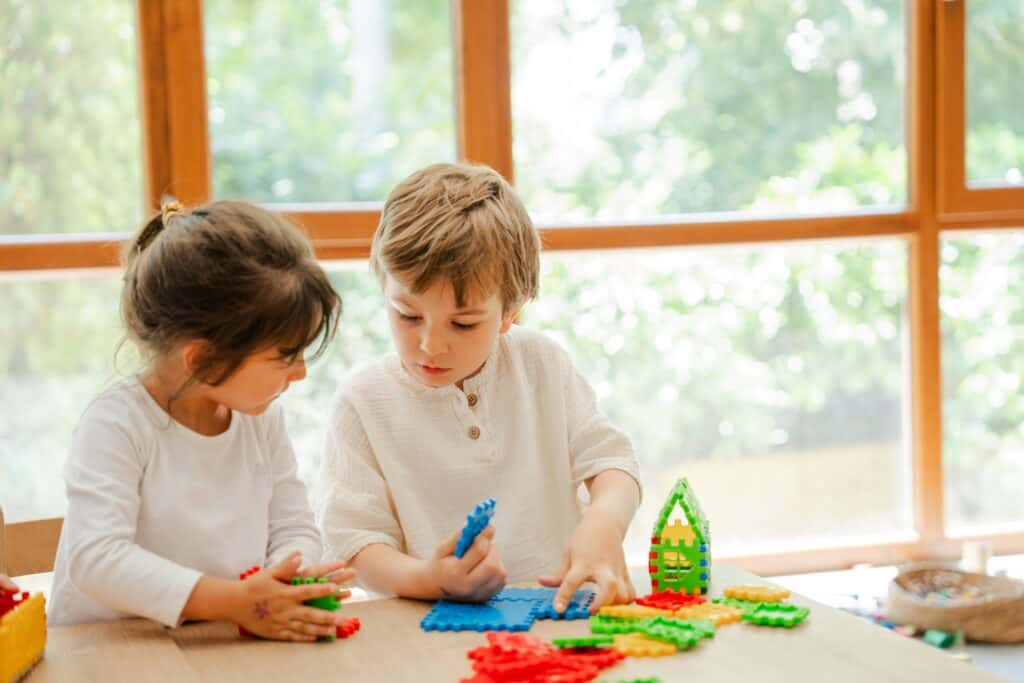 Two children play with building blocks at daycare, where vouchers and subsidies are often available for foster families who need child care services.