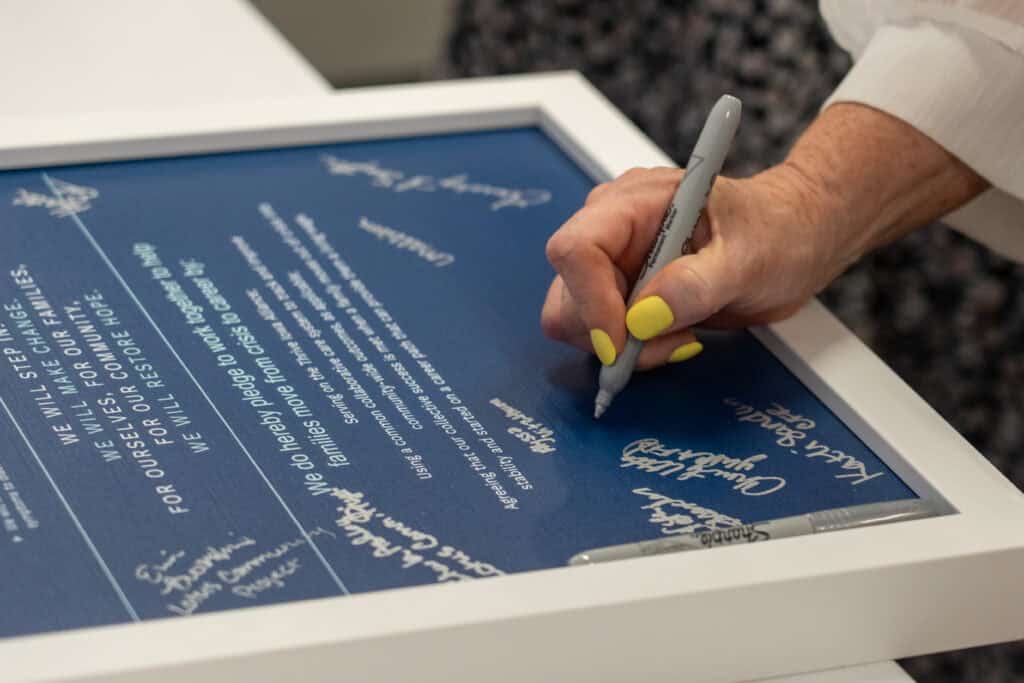 A local government leader signs the official agreement between Iowa and Restore Hope, launching Thrive Iowa.